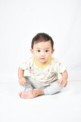 Fototapeta premium A cute baby with wide, curious eyes sits attentively, dressed in a charming animal-themed outfit. The baby's focused expression captures a moment of concentration and wonder.