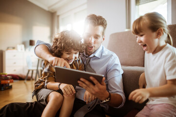 Happy father using tablet with two children enjoying family time at home