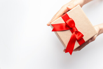 hands holding a gift box with red ribbon on white background with copy space