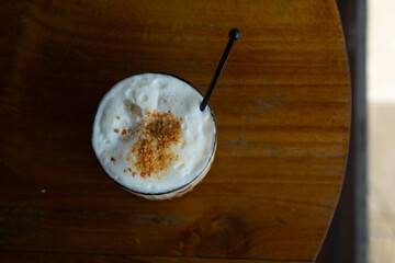 buttercloud coffee latte served on transparent glass, over wooden table surface, in cafe environment