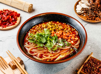 Hot and Sour Beans Noodles with coriander, red chilli, chopsticks and fork served in pot isolated on background side view of taiwanese food