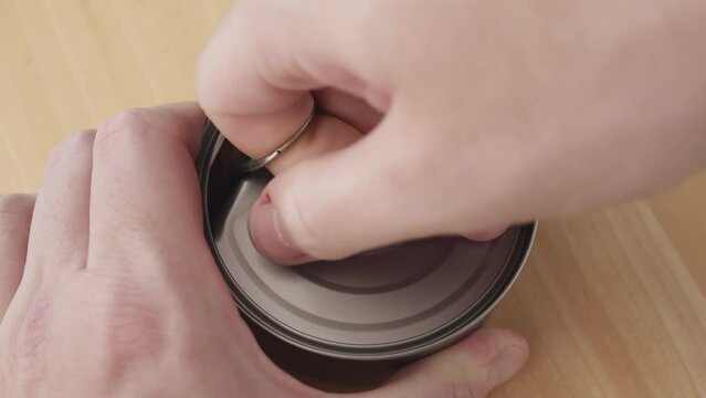 Overhead view on male hands opening a can of tuna.
