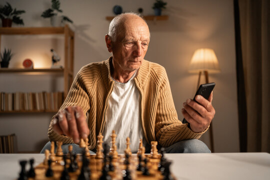 Man playing chess studying online on mobile phone