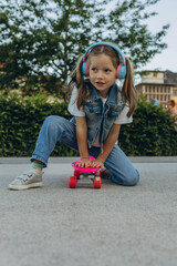 kid girl playing surf skate or skateboard in headphones