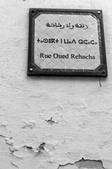Fez , street name tri lingual, arabic french and berber on ceramics panel. Medina old town, black and white picture. Morocco
