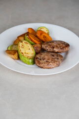 Ready-to-eat meatballs, cutlets or meat patties served on a plate with grilled vegetables. Home cooking, traditional recipes, and delicious meal presentation.