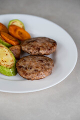 Ready-to-eat meatballs, cutlets or meat patties served on a plate with grilled vegetables. Home cooking, traditional recipes, and delicious meal presentation.