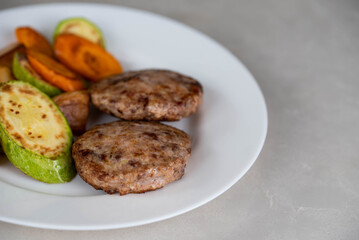 Ready-to-eat meatballs, cutlets or meat patties served on a plate with grilled vegetables. Home cooking, traditional recipes, and delicious meal presentation.