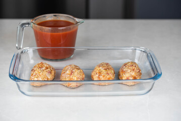 Preparing meat or cutlets patties with rice, baking them in a dish with tomato sauce. Home cooking, traditional recipes, and culinary preparation.