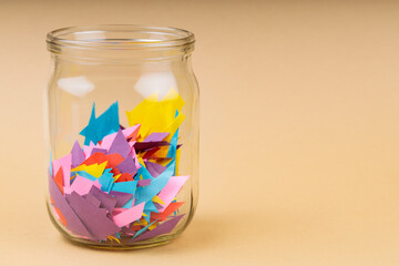 Glass Jar with Colorful Paper Scraps on Beige Background, Recycling Concept, Copy Space