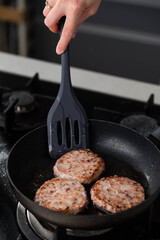 Meatballs or small meat patties cutlets sizzling in oil while frying in a pan on the stove. Concept of home cooking, traditional recipes, and culinary preparation