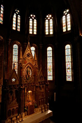Elaborate altar in front of colorful stained glass windows in gothic style shape inside the...