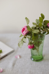 Moody romantic summer still life. beautiful floral bouquet with pink roses or rosehip flowers in a vase