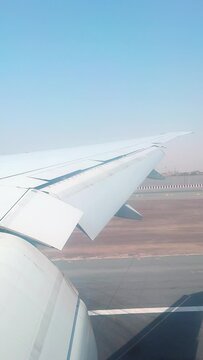 Aircraft window view of airplane landing on landing string in Dubai international airport UAE through morning fog of desert city. Closeup wing spoilers while braking. Travel on summer holiday vacation