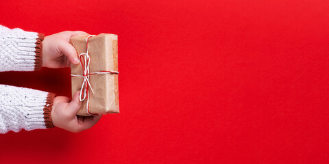 Baby hands holding gift box on red background. template, banner, christmas concept, copy space.
