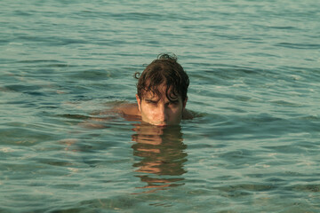 beautiful male model portrait in the sea, beautiful model swims in sea water