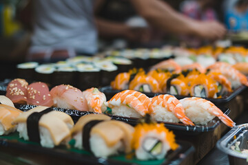 Sushi on a plate serving by chef at stall.