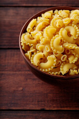 Pasta Creste di Gallo Bowl on Wooden Table, Copy Space