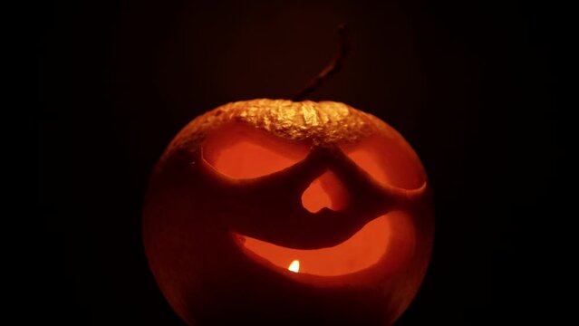Halloween pumpkin with scary face and warts. Celebrating Jack O Lantern pumpkin with candle illumination and glowing inside in the dark.