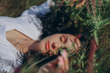 woman with black hair lies serenely in a Ukrainian field, surrounded by vibrant purple flowers, creating a striking contrast between her dark locks and the vivid floral landscape