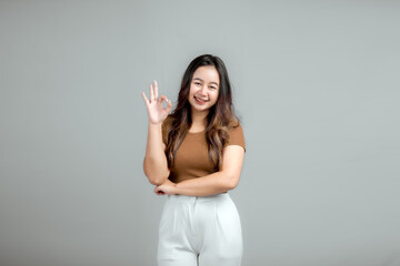 Portrait of a happy Asian Indonesian woman showing OK hand sign, isolated.