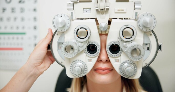 Optometrist, woman and phoropter for eye exam, hands and wellness in consultation room at hospital. People, doctor and patient with machine, lens and vision assessment for healthy eyesight in clinic