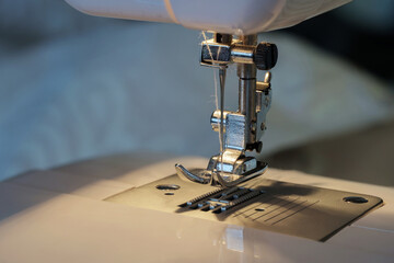 Close up shot of sewing machine steel foot with needle and thread, selective focus