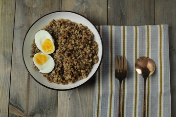 Grenne porridge, halves of eggs, fork, spoon on a napkin. The concept of a balanced diet. Proteins, carbohydrates