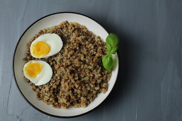 Buckwheat porridge with chicken egg, basil, top view. The concept of healthy food