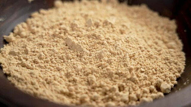 Peanut raw flour falling in slow motion into a wooden rustic bowl. Healthy fodmap diet baking nut ingredients. Rotation