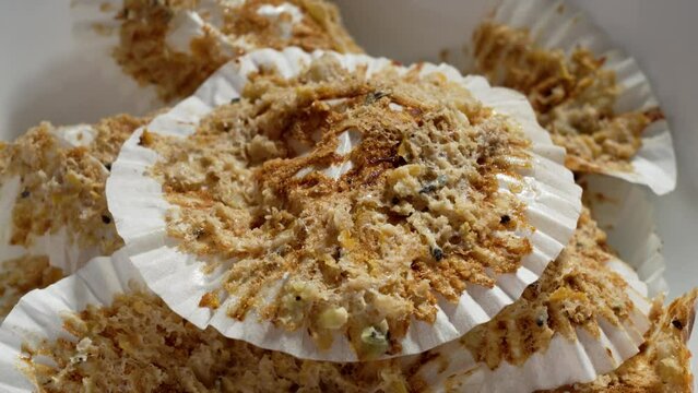 Leftover delicious sweet muffins in white paper molds in a ceramic kitchen plate. Rotation