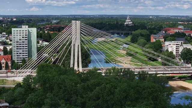 Flight towards the pylons of the Emperor Otto Bridge in Magdeburg. Sunny weather, cloudy sky. Apartment blocks, "Zollelbe" and "Bugaturm" in the background, cars driving on the bridge.