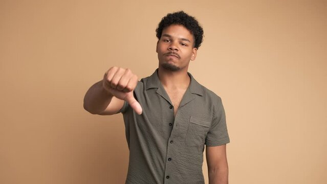 Sad man making thumbs down sign and shaking head in displeasure