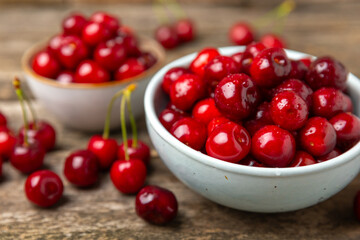 Cherries. Fresh ripe cherries with leaves on a textured wooden background. Fresh sweet organic cherry pile. Berries and fruits. Vegan. Healthy eating. Place for text. Copy space