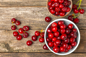 Cherries. Fresh ripe cherries with leaves on a textured wooden background. Fresh sweet organic cherry pile. Berries and fruits. Vegan. Healthy eating. Place for text. Copy space