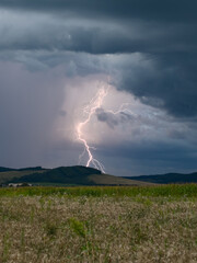 Lightning strikes a hilly landscape during the day