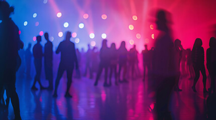 Fototapeta premium Blurred silhouettes of people dancing in a club with colorful lights