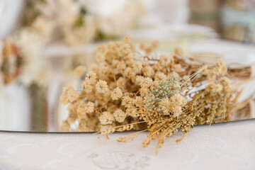 Close-up of a rustic dried flower bouquet on a reflective surface, showcasing the delicate details and natural beauty of the preserved blossoms, ideal for eco-friendly and timeless decor.