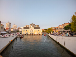 Aveiro, Portugal, August 21, 2021:  View of the main city canal in Aveiro and Vouga River with traditional Moliceiro boats (gondolas) on the canal. Moliceiro transporting tourists.