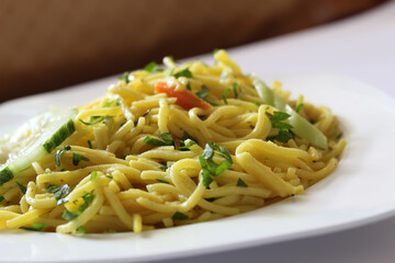 Close up shot of bami goreng garnished with celery and sliced carrots, mie goreng on a white plate with selective focus. Indonesian fried noodles with bokeh background.
