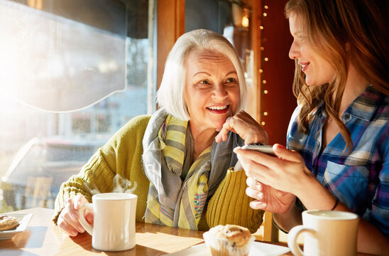 Smile, senior woman and daughter with smartphone in cafe with social media for memories with relax. Post, funny and tech savvy people in restaurant with coffee, muffin and sunshine in retirement.