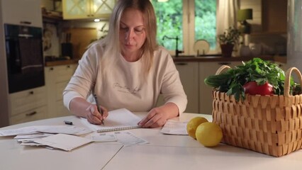 zoom in handheld shot of woman sitting at table managing budget inspecting paper checks at home expenses and taxes concept