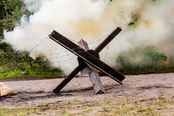 Background. Bomb exploding between the trees neer  Czech hedgehog. Reconstruction of battle from the Second World War. © krysek