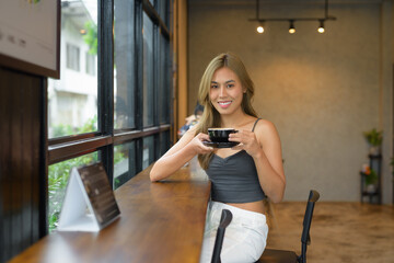Portrait of beautiful young woman happily holding coffee cup