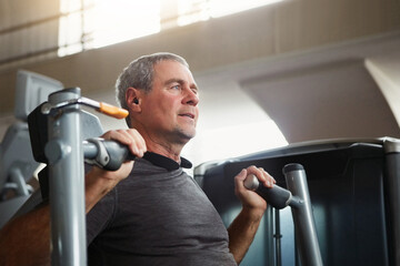 Mature man, chest press and workout with machine for fitness, training or indoor exercise at gym....