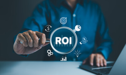 Analyzing Return on Investment (ROI) Concept. Businessman holding a magnifying glass with ROI and various financial icons, representing the analysis of return on investment and financial performance.