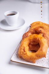 Drops of honey falling on the traditional Peruvian dessert called Picarones.