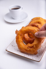 Fingers grabbing a donut named Picarones which is a traditional dessert from Peru.