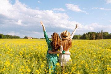 Two Beautiful women in dress enjoys summer time, spending leisure time, gathering wild flowers.