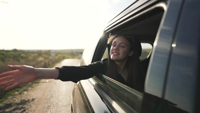 Happy woman feels freedom on road. Smiling woman enjoys fresh air with window down. Road trip adventure brings joy. Scenic travel moment capturing happiness. Woman celebrates freedom on road journey.